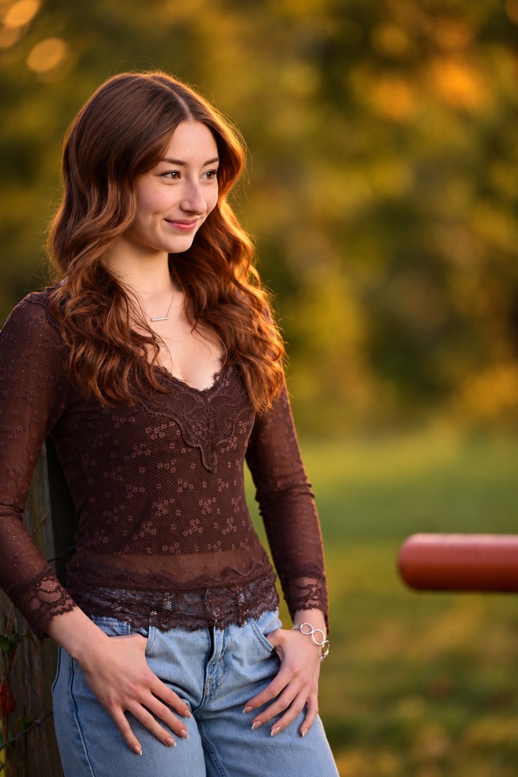 Senior portrait of a young woman leaning against a fence at golden hour