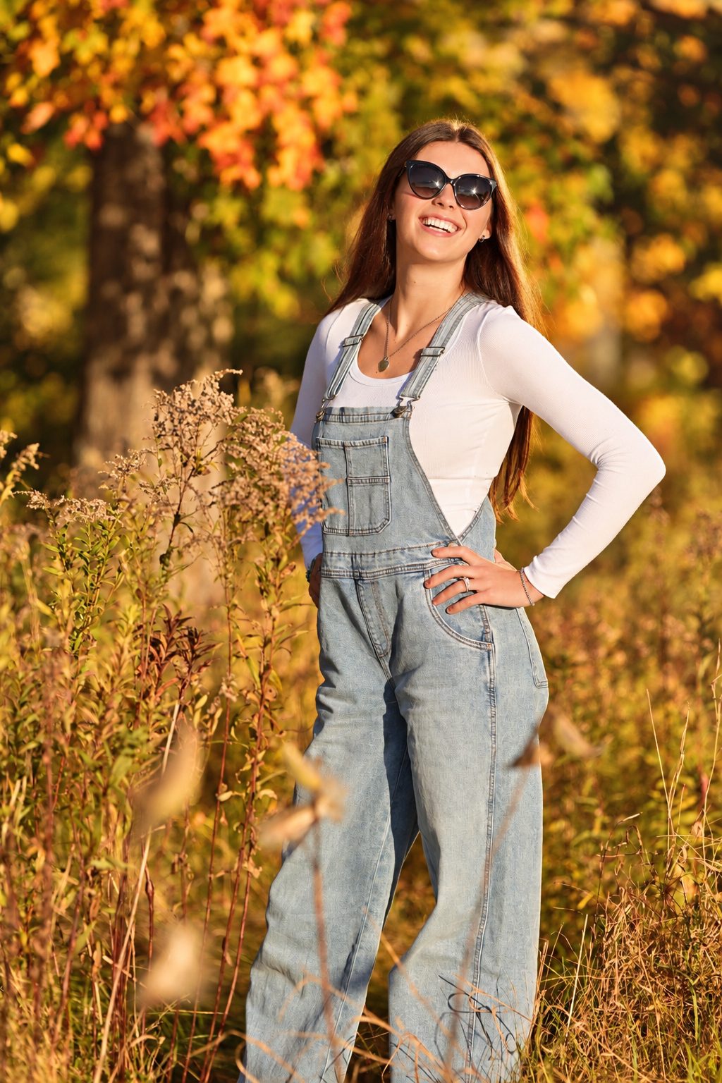 Young woman in sunglasses laughing in a golden field