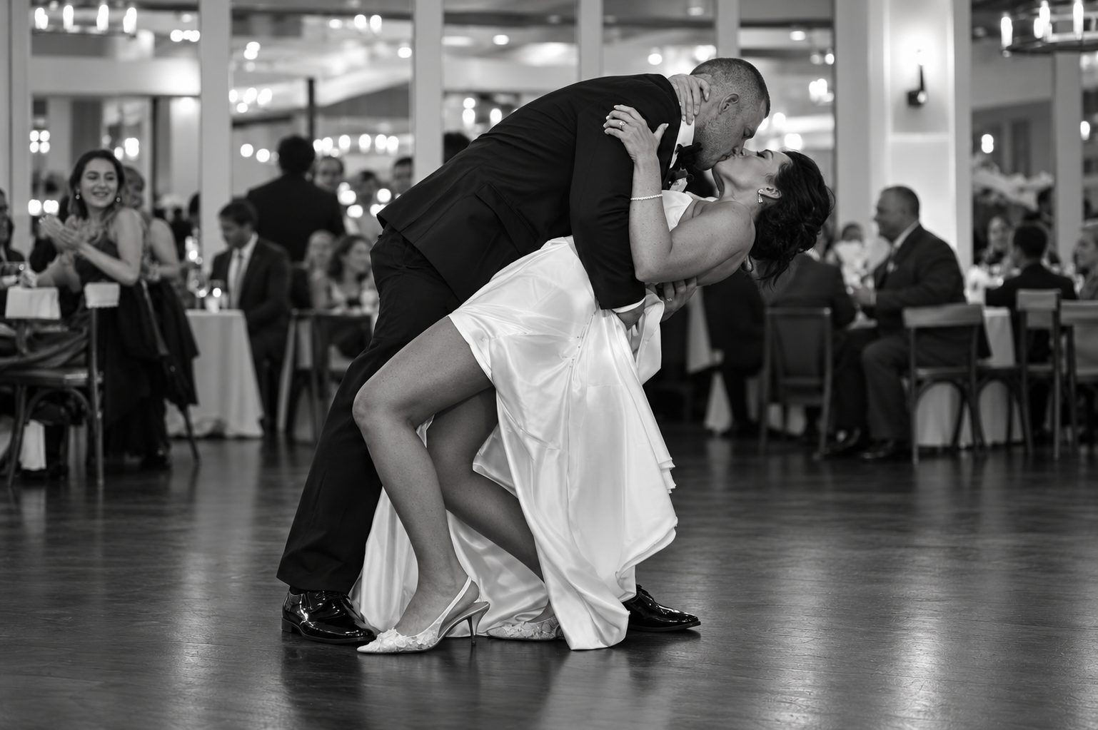 Black and white photo of bride and groom dipping and kissing on the dance floor